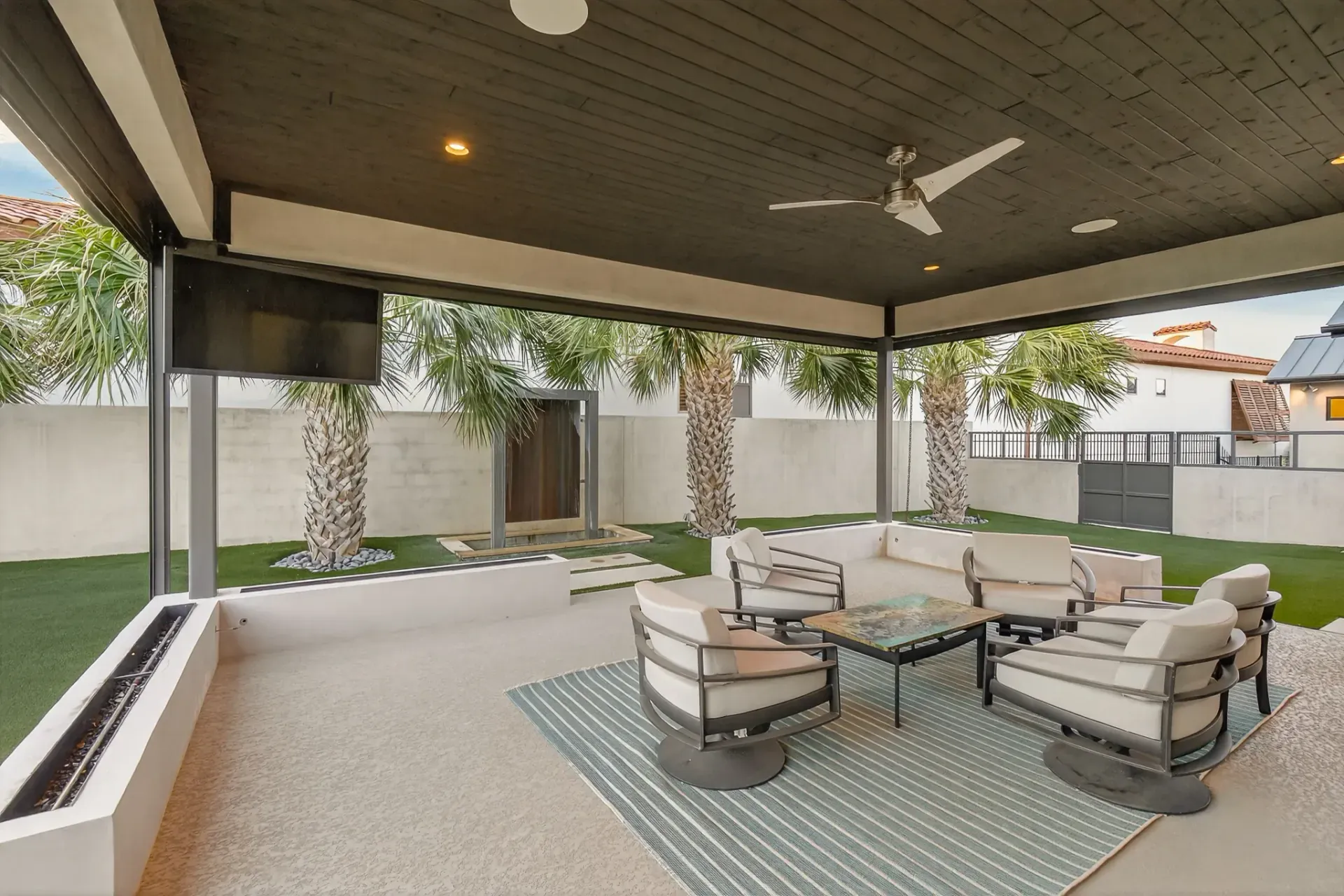 Covered patio with fireplace and turf yard